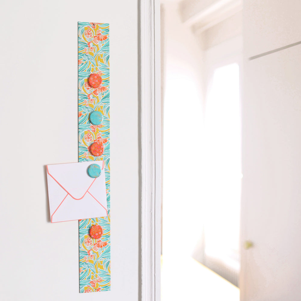 photo d'ambiance avec une vue d'ensemble du pêle-mêle tapissé du papier japonais aux motifs de fleurs « art nouveau » dans les tons jaune moutarde, vert d'eau et corail M988 adeline klam