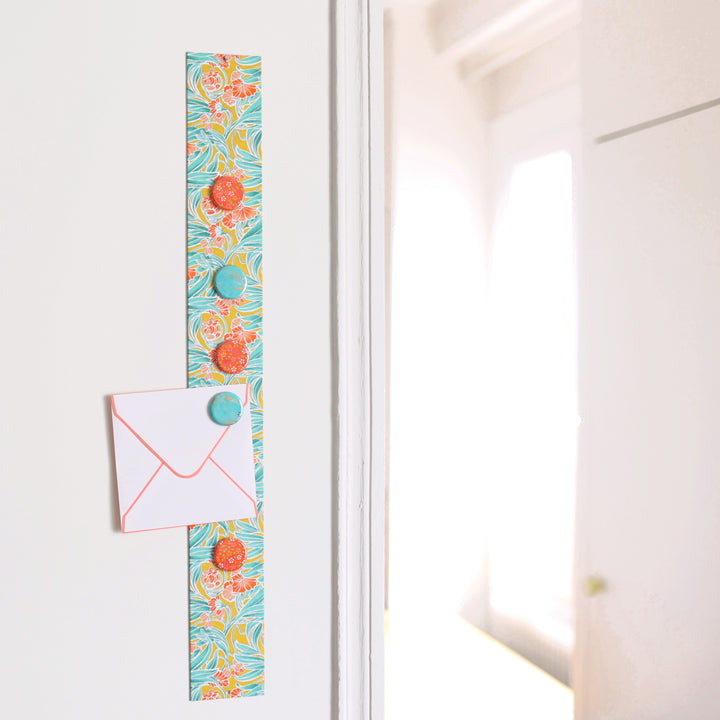 photo d'ambiance avec une vue d'ensemble du pêle-mêle tapissé du papier japonais aux motifs de fleurs « art nouveau » dans les tons jaune moutarde, vert d'eau et corail M988 adeline klam