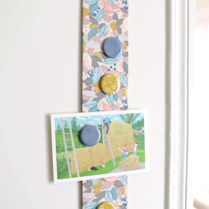 photo d'ambiance avec une vue zoomée du pêle-mêle tapissé du papier japonais aux motifs de feuilles, de baies et de fruits dans les tons rose pâle, bleu gris et jaune coing M896 adeline klam