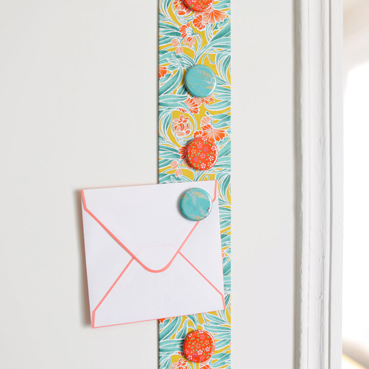 photo d'ambiance avec une vue zoomée du pêle-mêle tapissé du papier japonais aux motifs de fleurs « art nouveau » dans les tons jaune moutarde, vert d'eau et corail M988 adeline klam