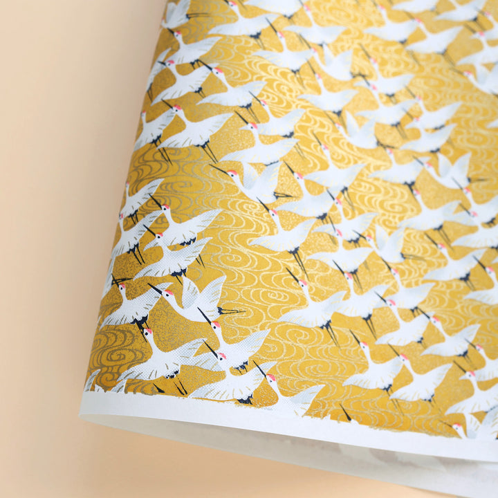 photo packshot d'une courbe du papier japonais yuzen chiyogami aux motifs d'envolée de grues blanches sur fond jaune adeline klam (M930)