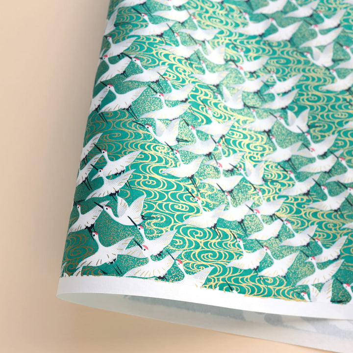 photo packshot d'une courbe du papier japonais yuzen chiyogami aux motifs d'envolée de grues blanches sur fond vert adeline klam (M931)