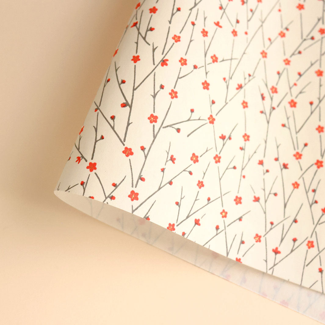 photo packshot d'une courbe de papier japonais yuzen chiyogami aux motifs de fines branches en fleurs dans les tons crème, rouge et gris foncé (M672)