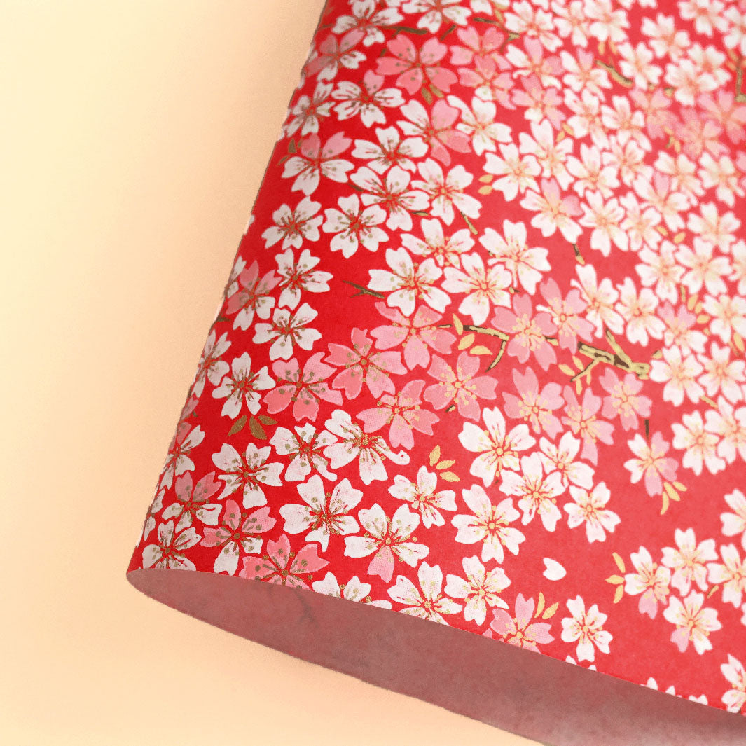 photo packshot d'une courbe de papier japonais yuzen chiyogami aux motifs de fleurs de cerisier dans les tons rouges, roses et blancs adeline klam (M623)