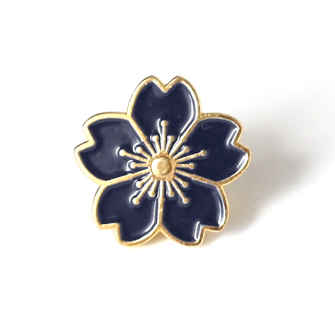 photo packshot d'un pin's en forme de fleur de cerisier bleu marine aux détails dorés
