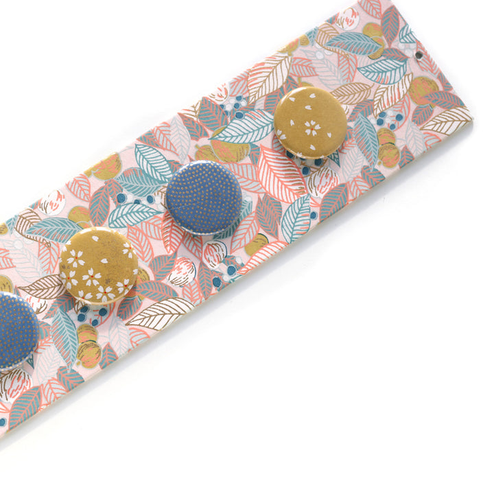 photo packshot avec une vue d'un détail du pêle-mêle tapissé du papier japonais aux motifs de feuilles, de baies et de fruits dans les tons rose pâle, bleu gris et jaune coing M896 adeline klam