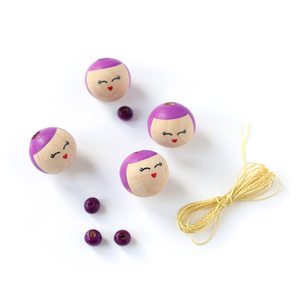 petites perles roses, perles « visages » souriants aux détails violets et fil doré