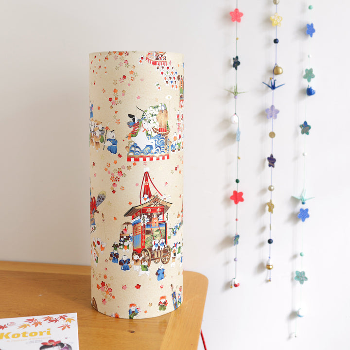 ambiance décorative de la lampe japonaise à poser aux motifs de scénettes d'un festival japonais dans les tons beiges, rouges, bleus, verts, orange et marrons adeline klam