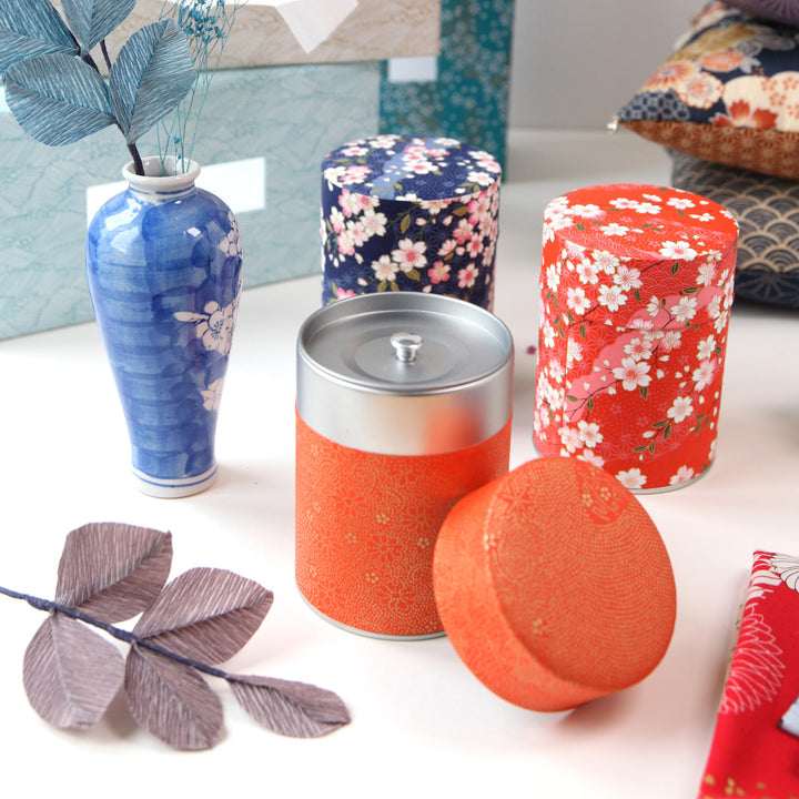 photo d'ambiance de boîtes à thé de forme cylindrique et de taille moyenne dans les tons rouges, orange et bleu nuit