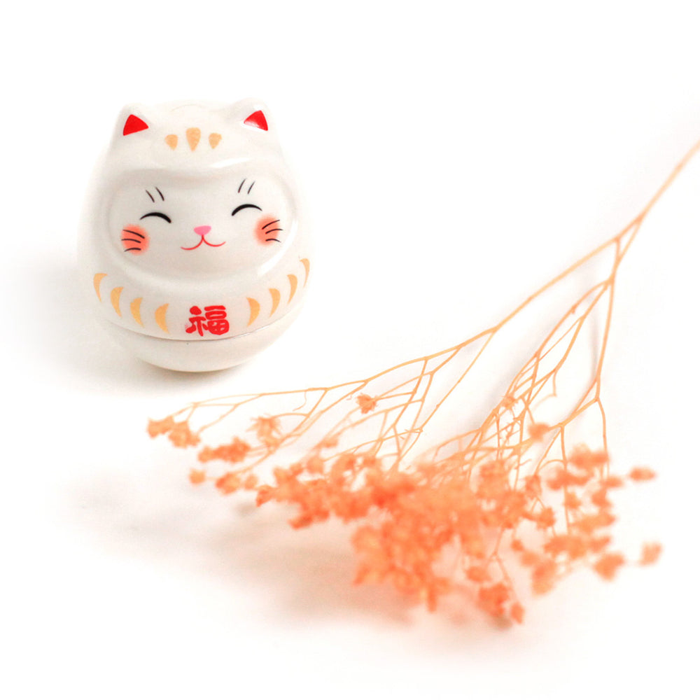 photo d'ambiance d'un culbuto japonais (ou kororin) en céramique en forme de daruma chat blanc