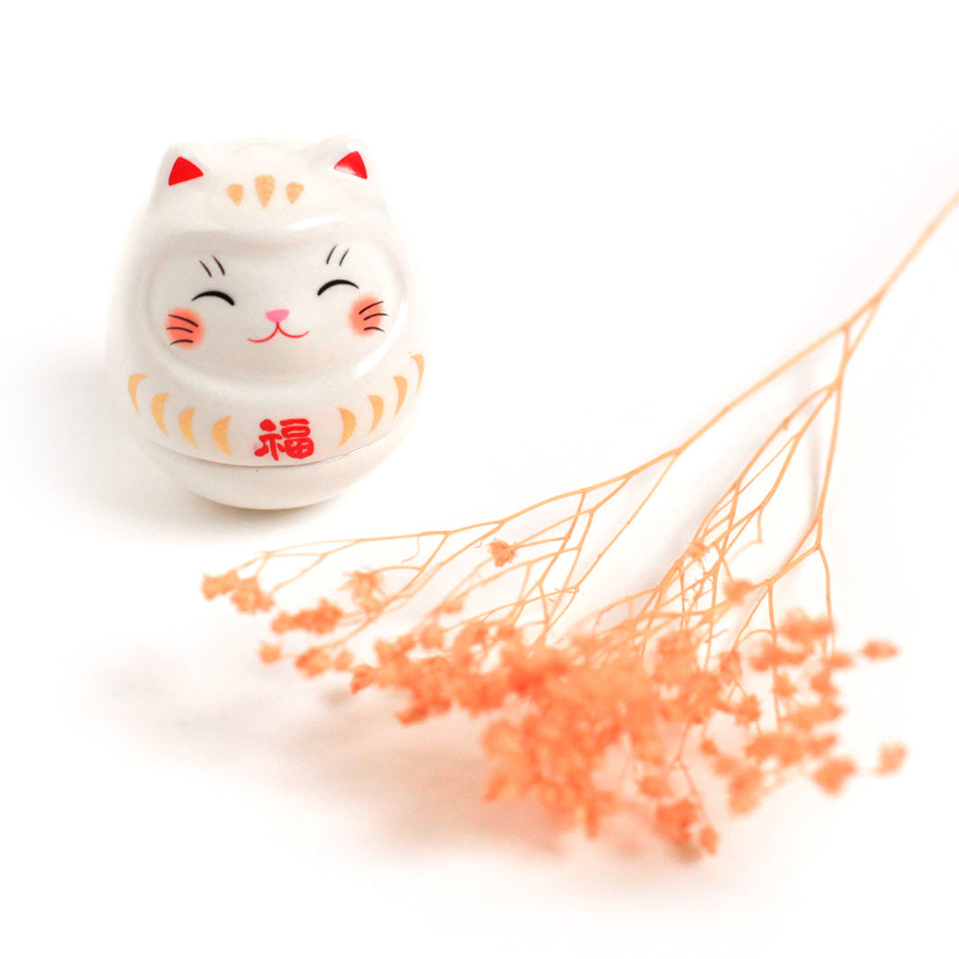 photo d'ambiance d'un culbuto japonais (ou kororin) en céramique en forme de daruma chat blanc