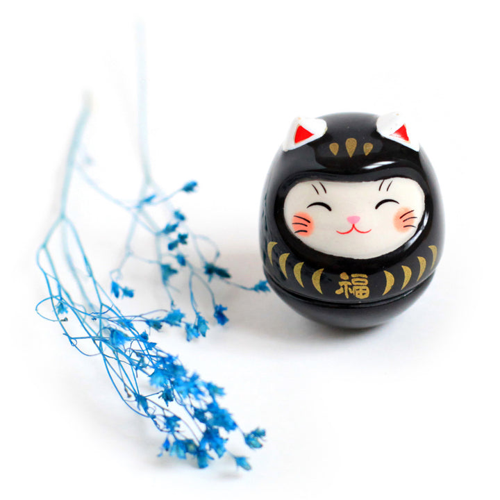 photo d'ambiance d'un culbuto japonais (ou kororin) en céramique en forme de daruma chat noir 