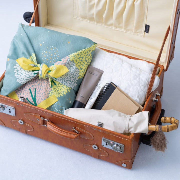 photo packshot d'affaires personnelles emballées avec le furoshiki au motif de forêt étoilée dans les tons jaune acidulé, vert de gris et roses adeline x musubi en 70cm par 70cm