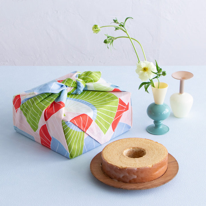 photo ambiance d'emballage cadeau de bento réalisé avec le furoshiki 70x70cm aux motifs d'éventails « toucan » dans les tons roses, bleus, verts, rouges adeline klam x musubi