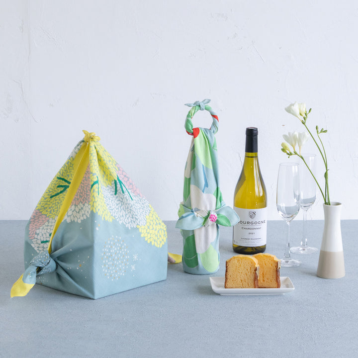 photo packshot d'un emballage cadeau réalisé avec le furoshiki au motif de forêt étoilée dans les tons jaune acidulé, vert de gris et roses adeline x musubi en 70cm par 70cm