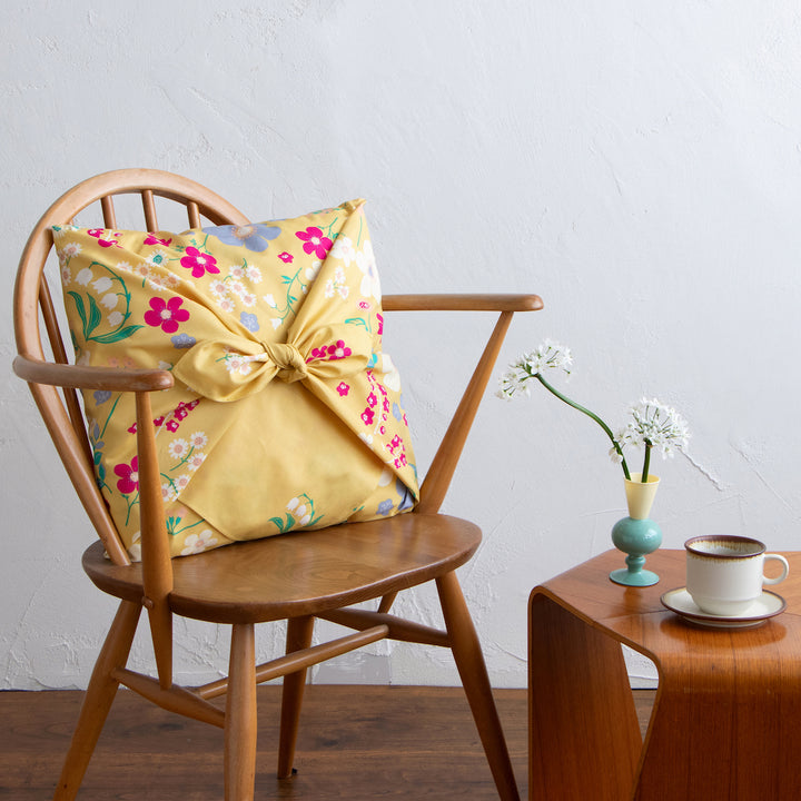 photo d'ambiance d'un emballage de coussin réalisé avec le furoshiki 100x100cm aux motifs garden « banane » dans les tons jaune banane adeline klam x musubi