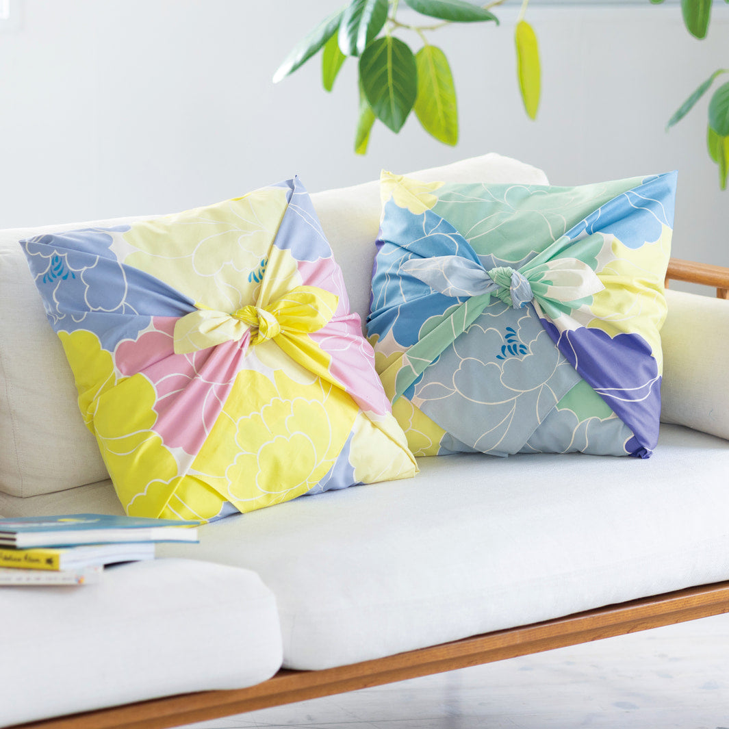 photo d'ambiance d'un coussin habillé avec le furoshiki au motif de pivoines dans les tons jaune pâle et acidulé, roses et bleu gris adeline x musubi en 100cm par 100cm