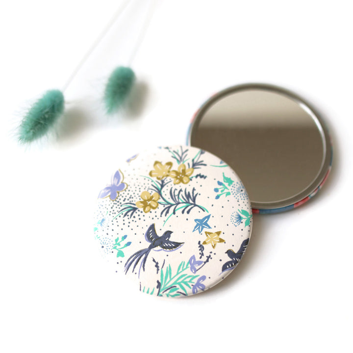 photo packshot du recto du miroir de poche tapissé de papier japonais aux motifs de fleurs, d'oiseaux et de papillons dans les tons blanc cassé, bleu marine, verts, mauve et jaunes (M1003) adeline klam