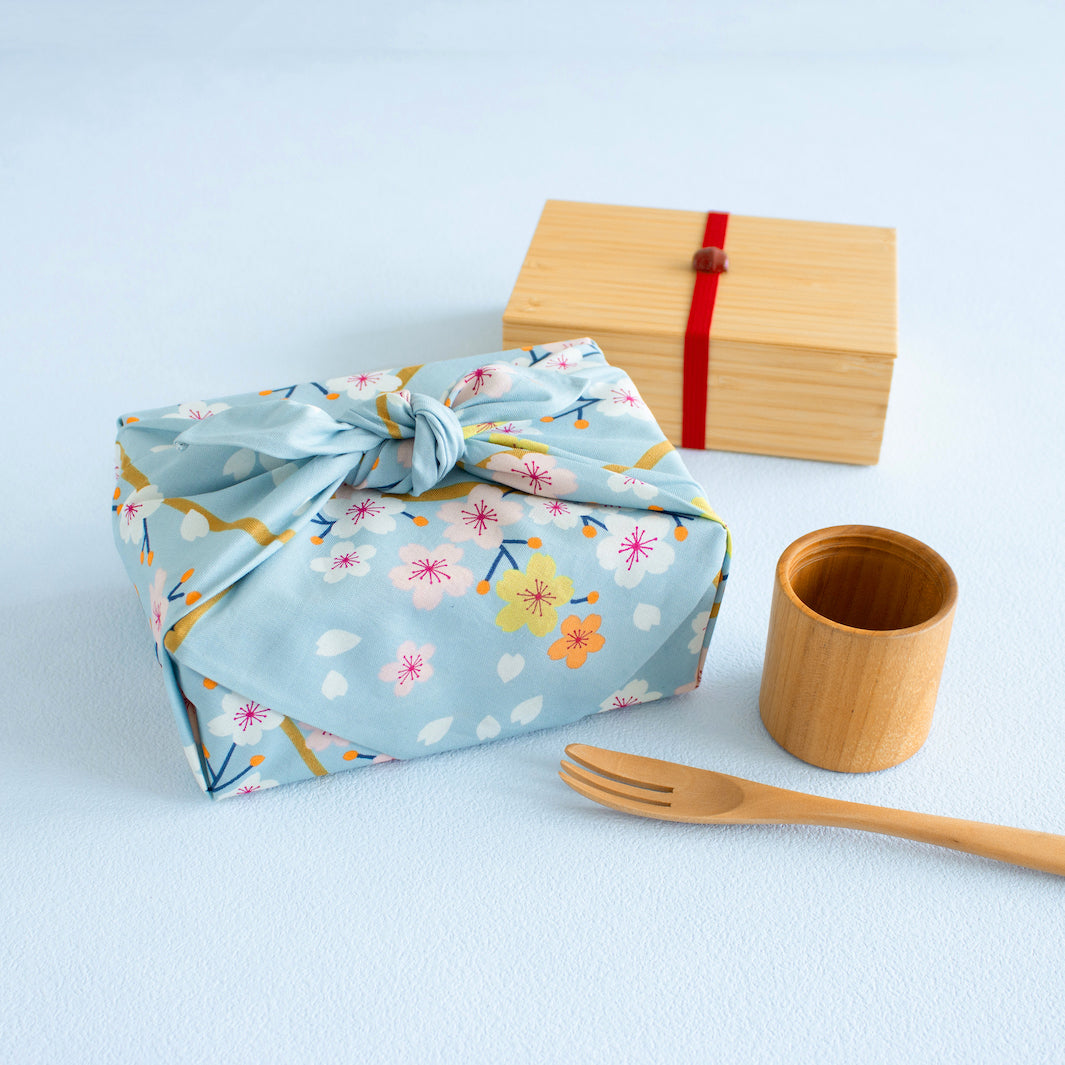 photo d'ambiance d'un emballage de bento réalisé avec le furoshiki 50x50cm aux motifs cerisier « glacier » dans les tons bleu ciel adeline klam x musubi