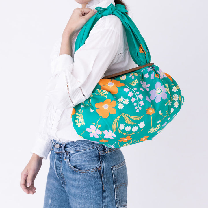 photo d'ambiance d'un sac avec anse réalisé avec le furoshiki « jardin » dans les tons vert canard, jaunes, violet lilas et orange adeline x musubi en 100cm par 100cm