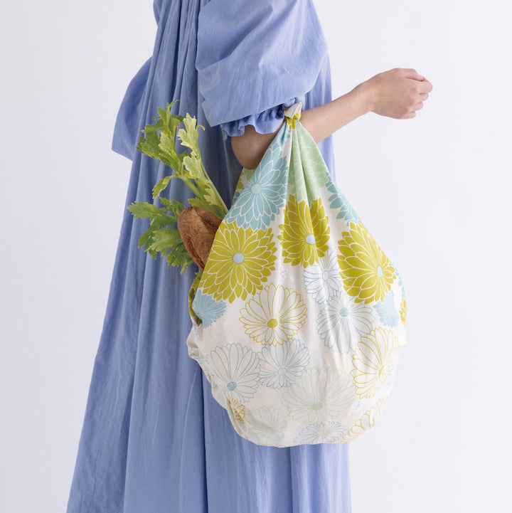 photo d'ambiance d'un sac porté réalisé avec le furoshiki 100x100cm aux motifs de chrysanthèmes « mousse » dans les tons beiges, jaune vert, bleu glacier et vert amande adeline klam x musubi