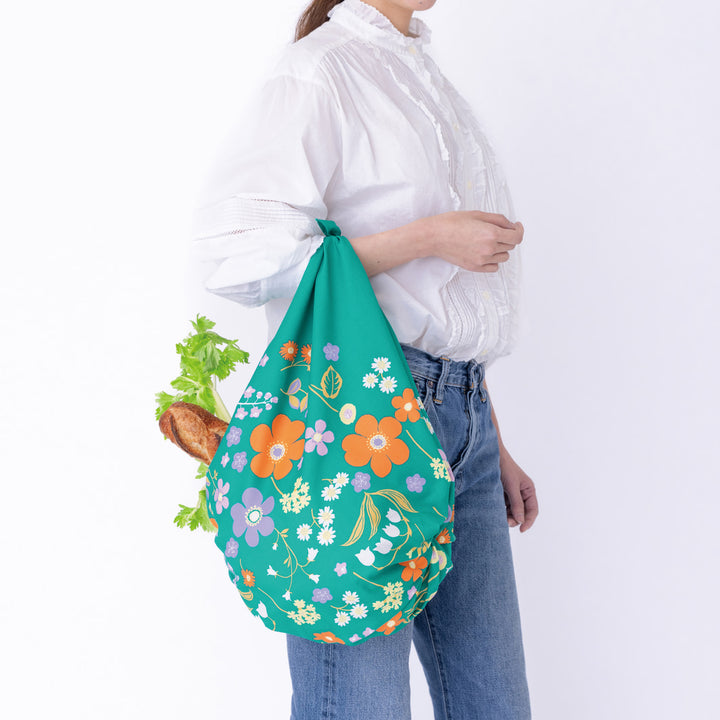 photo d'ambiance d'un sac simple réalisé avec le furoshiki « jardin » dans les tons vert canard, jaunes, violet lilas et orange adeline x musubi en 100cm par 100cm