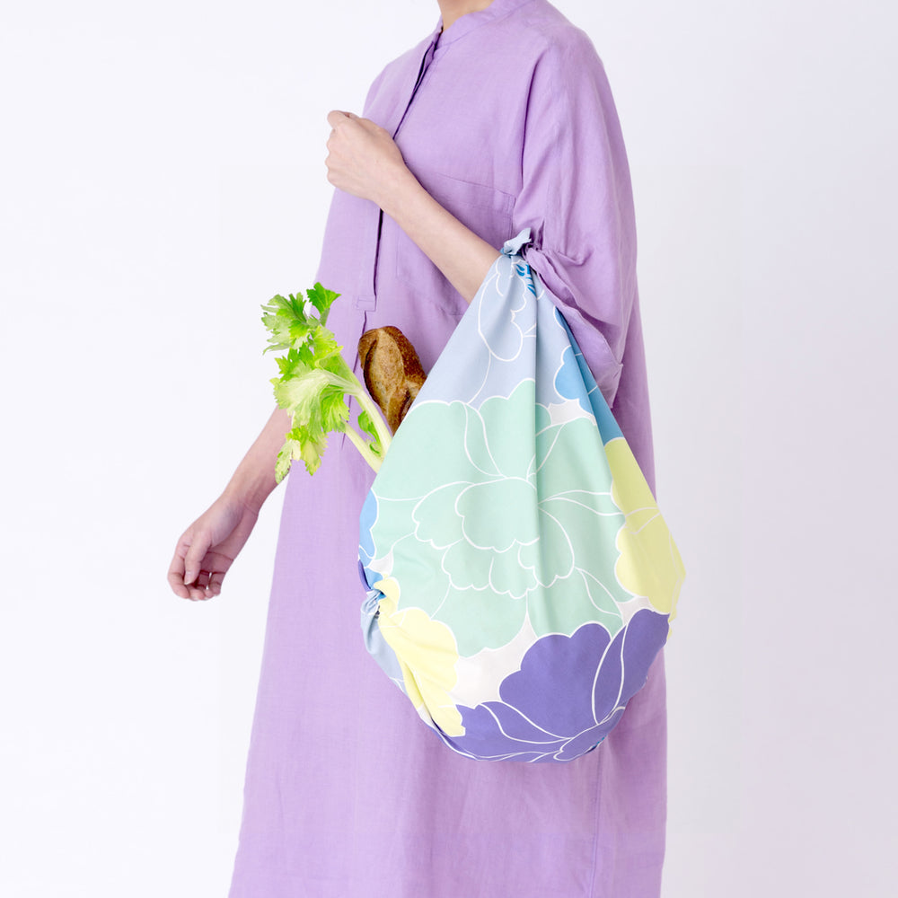 photo d'ambiance d'un sac simple réalisé avec le furoshiki au motif de pivoines dans les tons jaune acidulé, bleus, vert d'eau, violets adeline x musubi en 100cm par 100cm