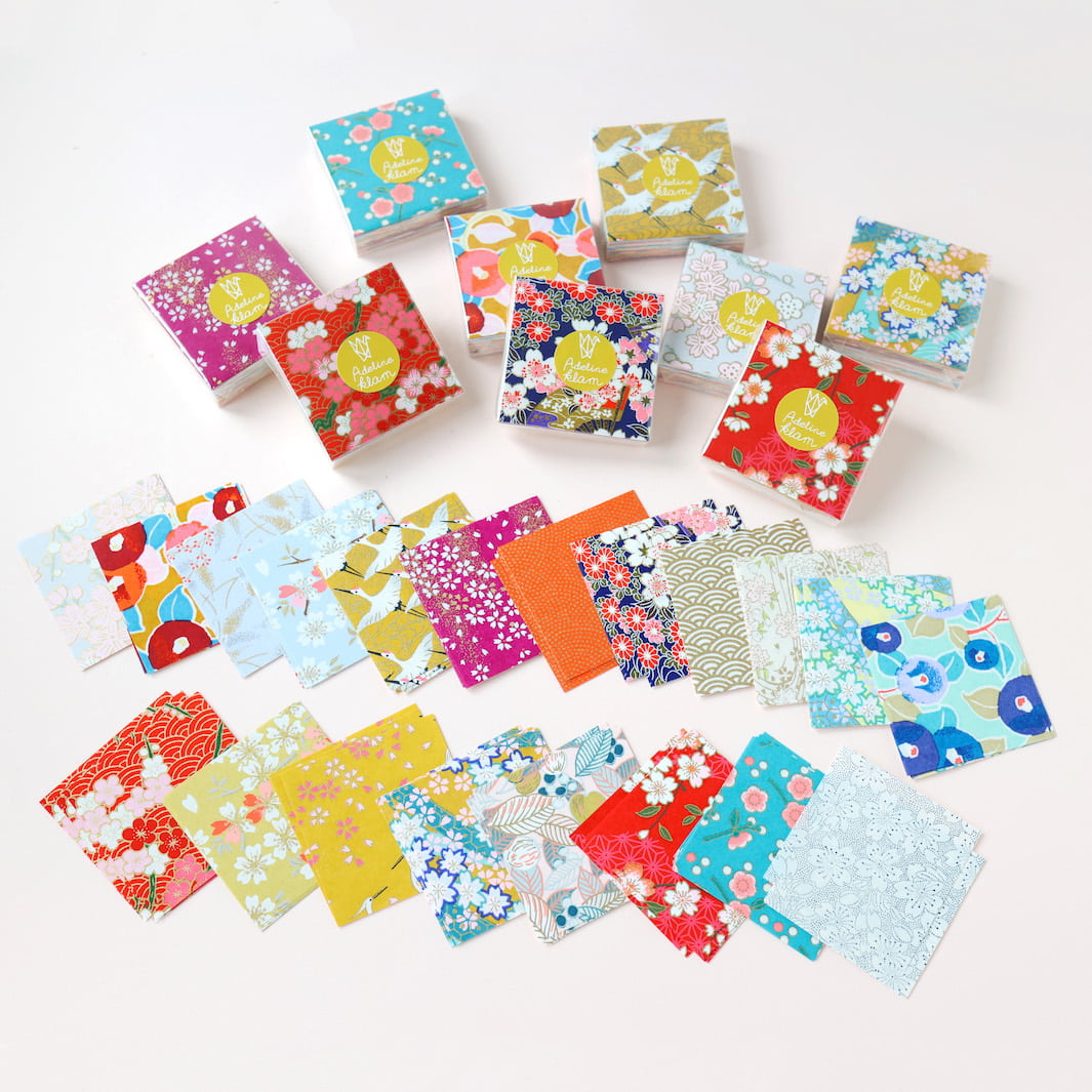 photo d'ambiance de sets de 100 carrés de papiers japonais adeline klam de 6cm par 6cm dans les tons jaunes, orange, rouges, roses et bleu turquoise « multifruits »