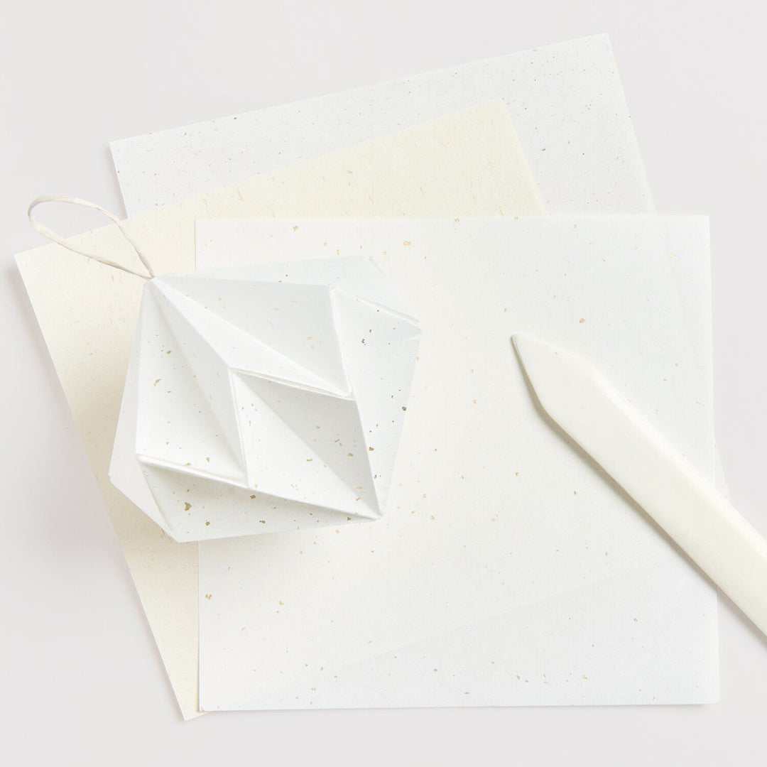 photo d'ambiance du set de 30 papiers origami unis mouchetés blancs, beiges et ivoires de 15cm par 15cm rico design