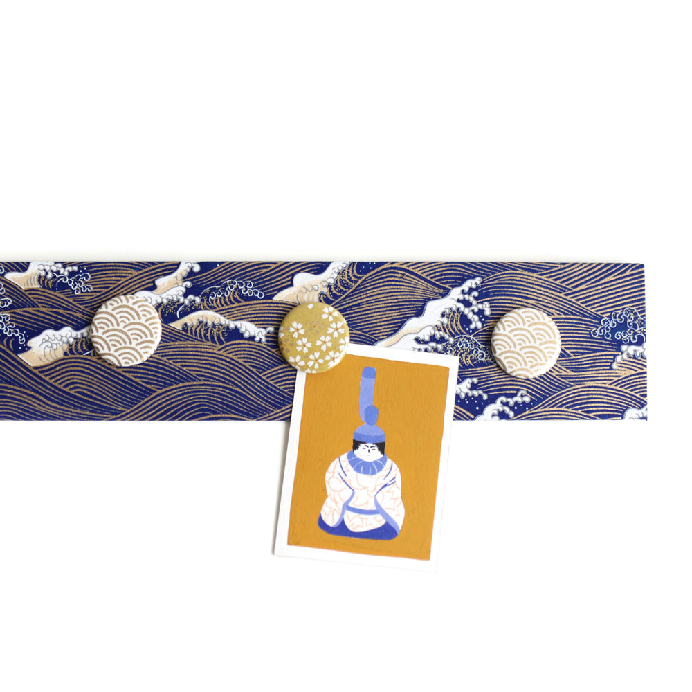 photo d'ambiance avec une vue d'ensemble du pêle-mêle tapissé du papier japonais aux motifs de vagues et d'écumes dans les tons bleu nuit, jaune clair et dorés M851 adeline klam