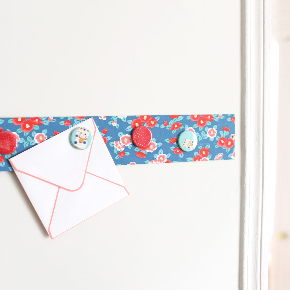 photo d'ambiance avec une vue zoomée du pêle-mêle tapissé du papier japonais aux motifs de camélias dans les tons bleu foncé, rouge orangé, roses et vert d'eau M956 adeline klam