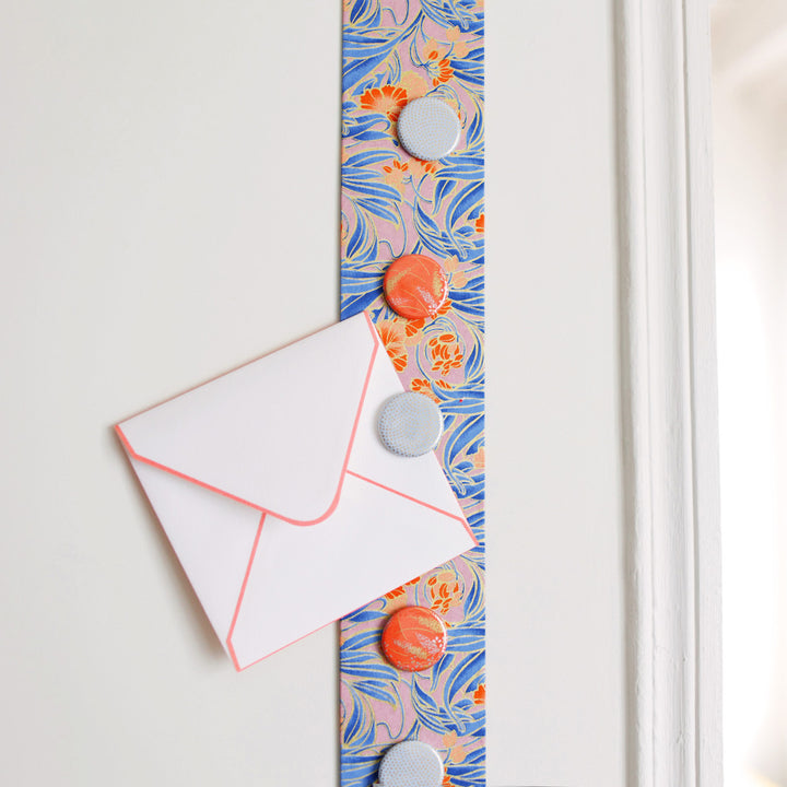 photo d'ambiance avec une vue zoomée du pêle-mêle tapissé du papier japonais aux motifs de fleurs « art nouveau » dans les tons mauve, bleus et et corail M988 adeline klam