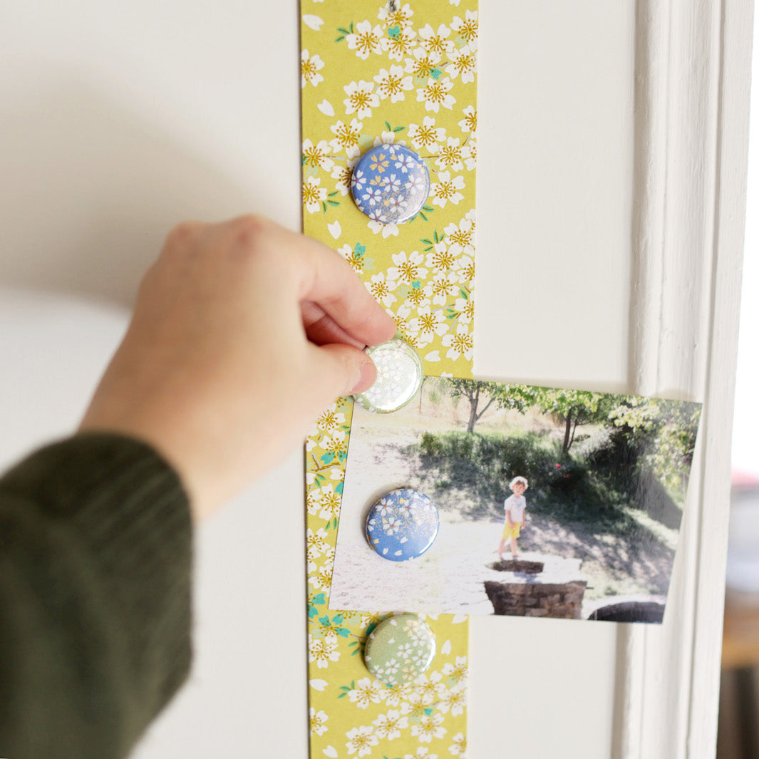 photo d'ambiance avec une vue zoomée du pêle-mêle tapissé du papier japonais aux motifs de fleurs de cerisier dans les tons blancs, vert d'eau, bleu turquoise et jaune moutarde M578 adeline klam