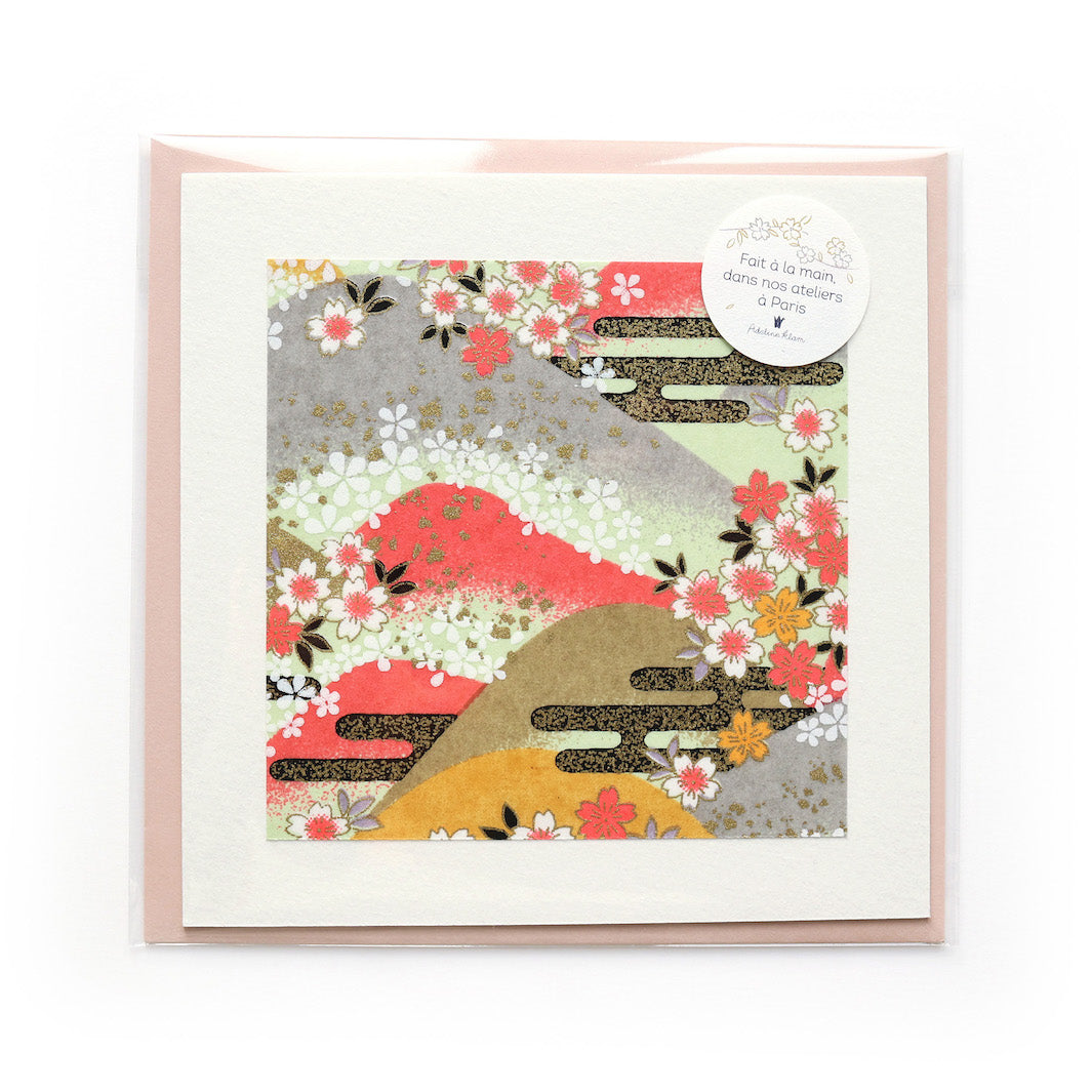 photo packshot du packaging de la carte carrée double habillée d'un carré de papier japonais de 13cm au motifs de montagnes et de fleurs de cerisier dans les tons roses, jaunes, verts, gris et doré (M1033) et son enveloppe assortie adeline klam