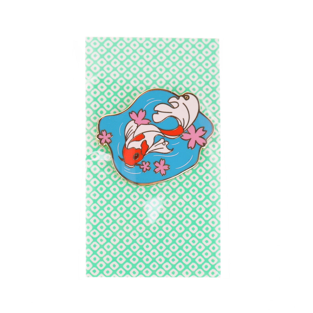 photo packshot du packaging du pin's en forme de poissons japonais blanc et orange, de fleurs de cerisier roses et d'étang bleu
