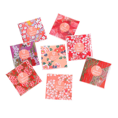 photo packshot de 100 papiers origami de 6cm par 6cm aux motifs variés dans les tons rouges, rouge orangé, corail et roses de la gamme « grenadine » adeline klam