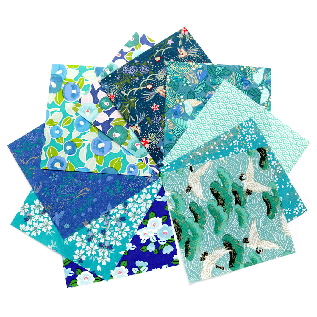 photo packshot de l'assortiment de papiers japonais du set de 7 carrés de papiers japonais adeline klam de 12cm par 12cm dans les tons bleu canard, vert d'eau, bleu nuit, turquoise et violets « paon »