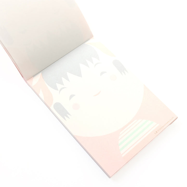 photo packshot de biais de l'intérieur du bloc-notes de 60 feuilles aux motifs de kokeshi sur fond rouge