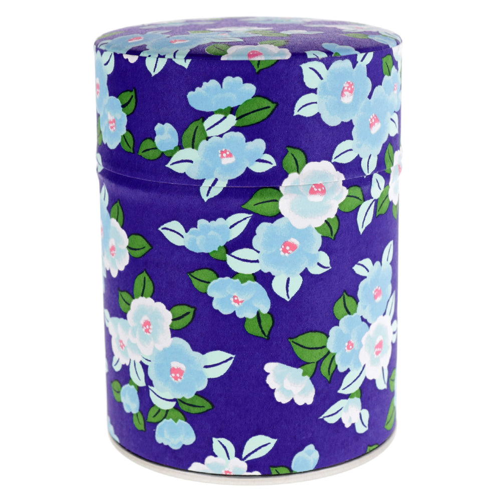 photo packshot d'une boîte à thé cylindrique ouverte tapissée de papier japonais aux motifs de camélias tsubaki dans les tons bleu violet, bleu ciel et verts (M955) adeline klam