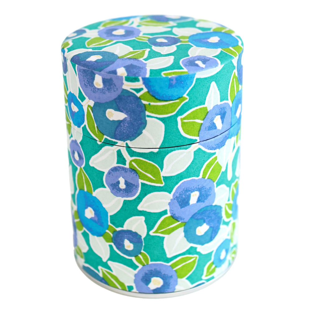 photo packshot d'une boîte à thé cylindrique fermée tapissée d'un papier japonais aux motifs de camélias dans les tons vert clair, foncé et menthe, bleu moyen et gris (M798) adeline klam