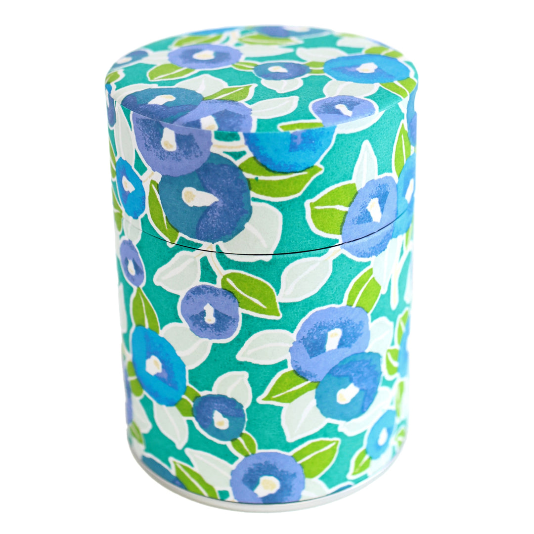 photo packshot d'une boîte à thé cylindrique fermée tapissée d'un papier japonais aux motifs de camélias dans les tons vert clair, foncé et menthe, bleu moyen et gris (M798) adeline klam