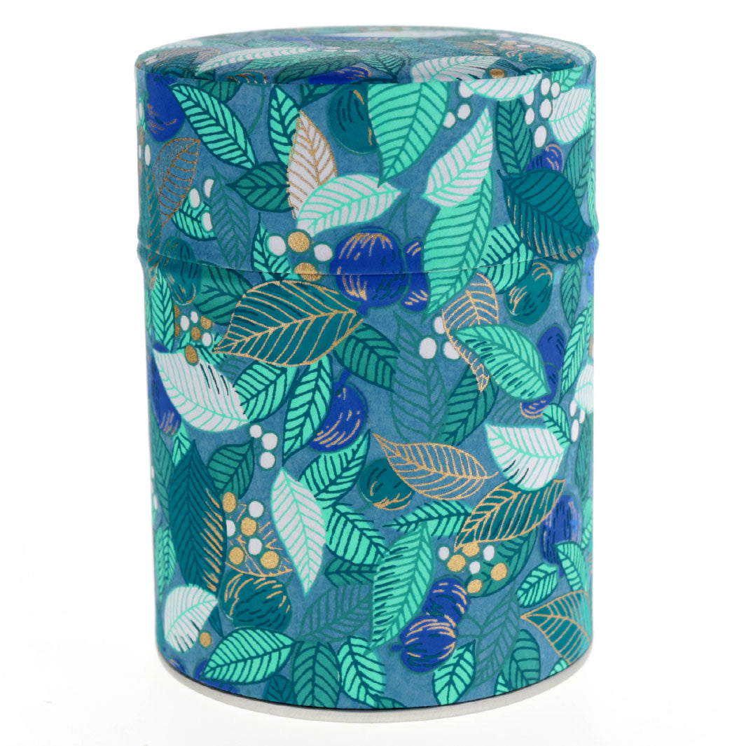 photo packshot d'une boîte à thé cylindrique fermée tapissée de papier japonais aux motifs de feuilles, de baies et de fruits dans les tons bleu canard, vert d'eau et vert foncé (M935) adeline klam