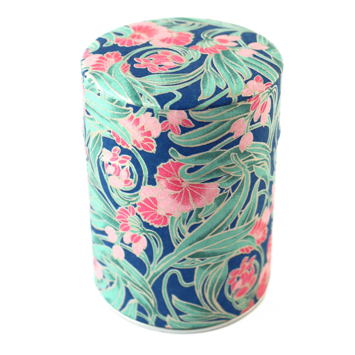photo packshot d'une boîte à thé cylindrique fermée tapissée d'un papier japonais aux motifs de fleurs « art nouveau » dans les tons bleu foncé, verts et roses (M947) adeline klam
