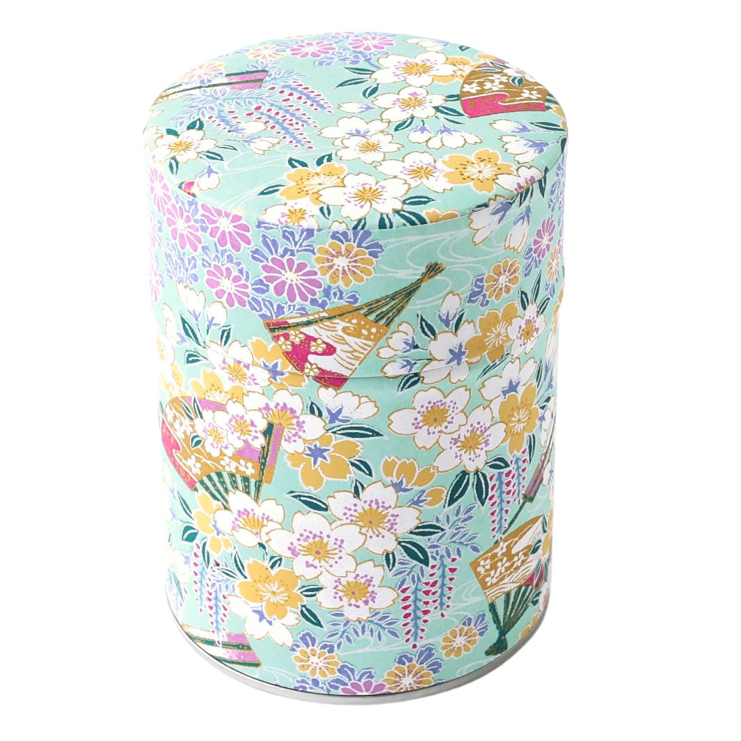 photo packshot d'une boîte à thé cylindrique fermée tapissée d'un papier japonais aux motifs de fleurs de cerisier, de chrysanthèmes, de glycines et d'éventails vert d'eau, jaunes, mauve, parme et blancs (M1017) adeline klam