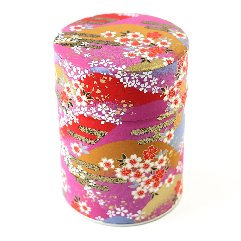 photo packshot d'une boîte à thé cylindrique fermée tapissée d'un papier japonais aux motifs de de fleurs, de montagnes et de nuages dans les tons rouges, roses, violets et dorés (M948) adeline klam