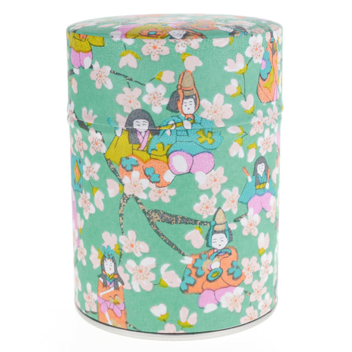 photo packshot d'une boîte à thé cylindrique fermée tapissée de papier japonais aux motifs de poupées d'hina matsuri et de fleurs de pêcher vert menthe, rose mauve, orange clair, vert acidulé et bleus (M1004) adeline klam