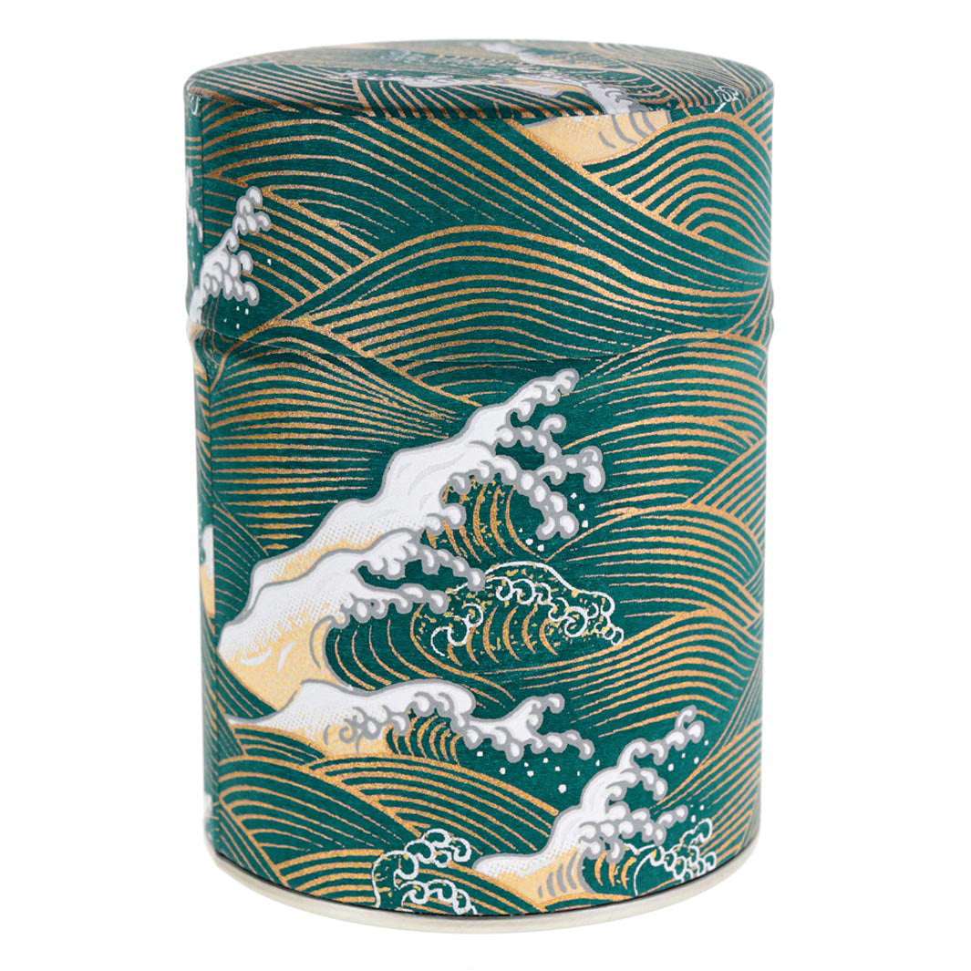 photo packshot d'une boîte à thé cylindrique fermée tapissée de papier japonais aux motifs de vagues et d'écumes bleu canard, beiges et dorés (M941) adeline klam