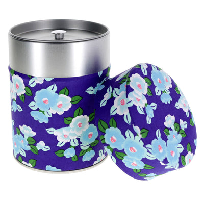 photo packshot d'une boîte à thé cylindrique ouverte tapissée de papier japonais aux motifs de camélias tsubaki dans les tons bleu violet, bleu ciel et verts (M955) adeline klam