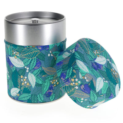 photo packshot d'une boîte à thé cylindrique ouverte tapissée de papier japonais aux motifs de feuilles, de baies et de fruits dans les tons bleu canard, vert d'eau et vert foncé (M935) adeline klam