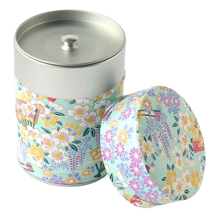 photo packshot d'une boîte à thé cylindrique ouverte tapissée d'un papier japonais aux motifs de fleurs de cerisier, de chrysanthèmes, de glycines et d'éventails vert d'eau, jaunes, mauve, parme et blancs (M1017) adeline klam